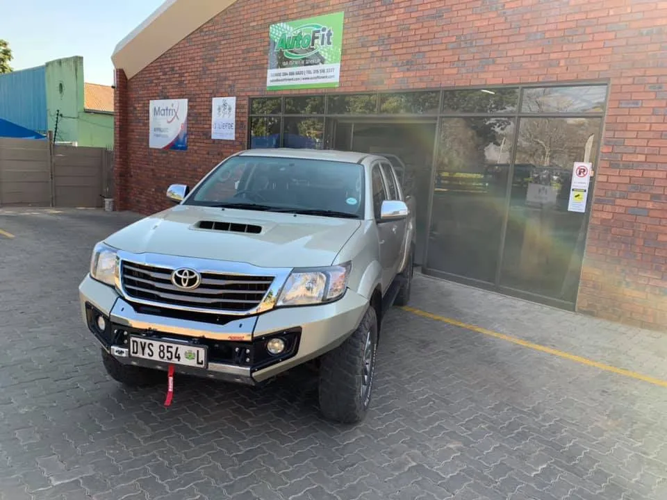 Toyota Hilux double cab fitted with a heavy-duty steel replacement front bumper (bull bar) with integrated lights and recovery points.