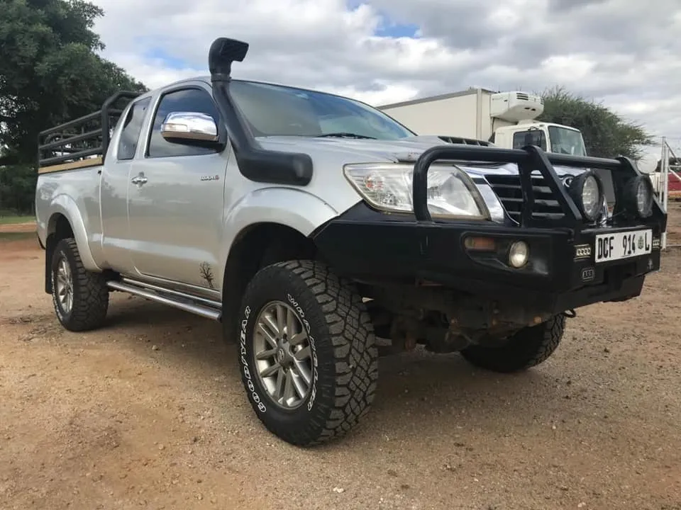 Silver Toyota Hilux Vigo extra cab fitted with a black ARB bull bar, Safari snorkel, and rear cattle rails