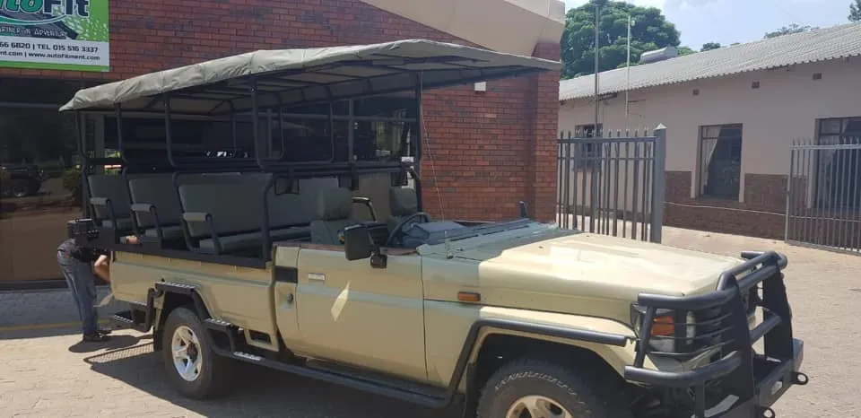 Tan Toyota Land Cruiser 79 single cab game drive vehicle conversion with open-sided passenger seating